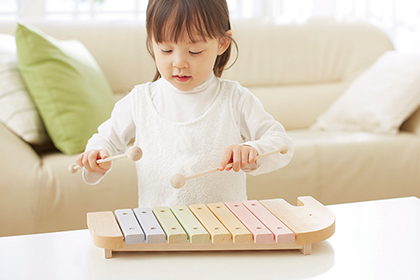 木製のシロフォンを叩く子ども