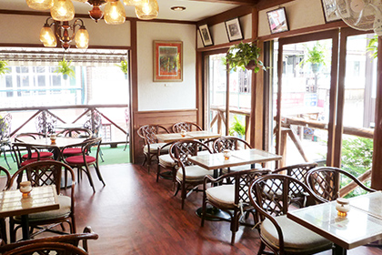 ミカド珈琲軽井沢旧通店2階風景。各てーぬるには椅子が4脚置かれ、室内とテラスには仕切りが無く開放的な空間。